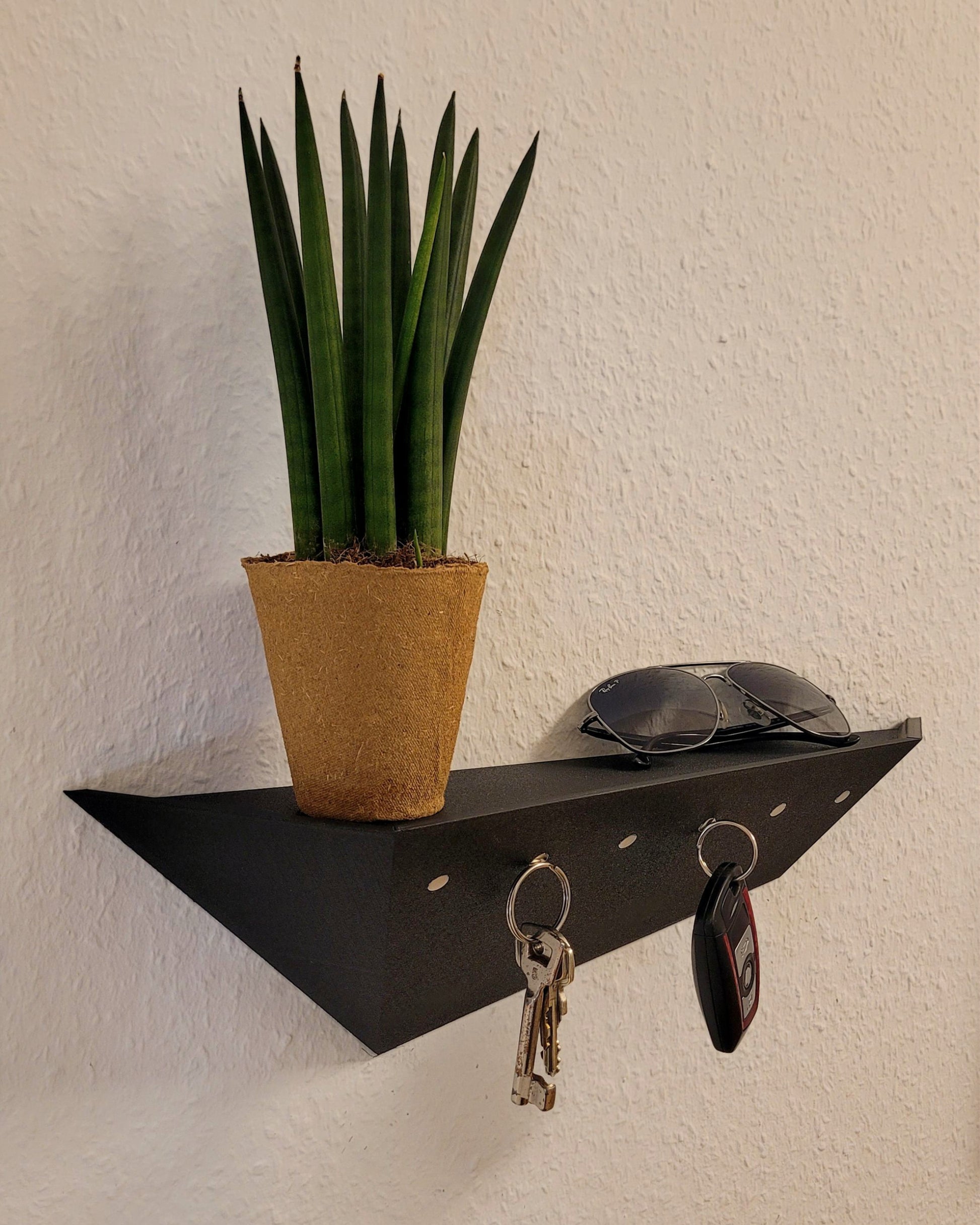Das Treeboard Schlüsselbrett im Eingangsbereich. Mehrere Schlüssel haften magnetisch am schwebend montierten Board. Eine Sonnenbrille und eine kleine Pflanze liegen auf der integrierten Ablage. Das Video demonstriert die starke Magnetkraft, die verdeckte Wandmontage und das minimalistische Design des Treeboards.